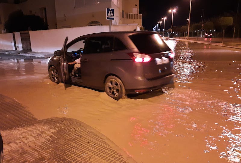 Un coche circula con dificultad por las calles inundadas de El Mojón